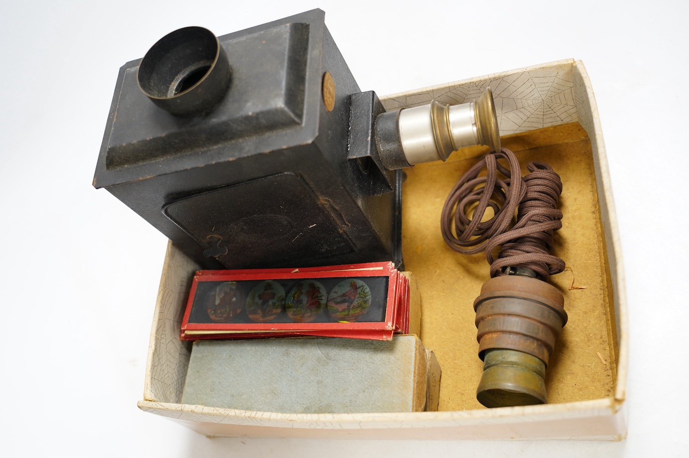 A late 19th century child's tinplate magic lantern with a selection of German slides, magic lantern 21cm high. Condition - fair to good